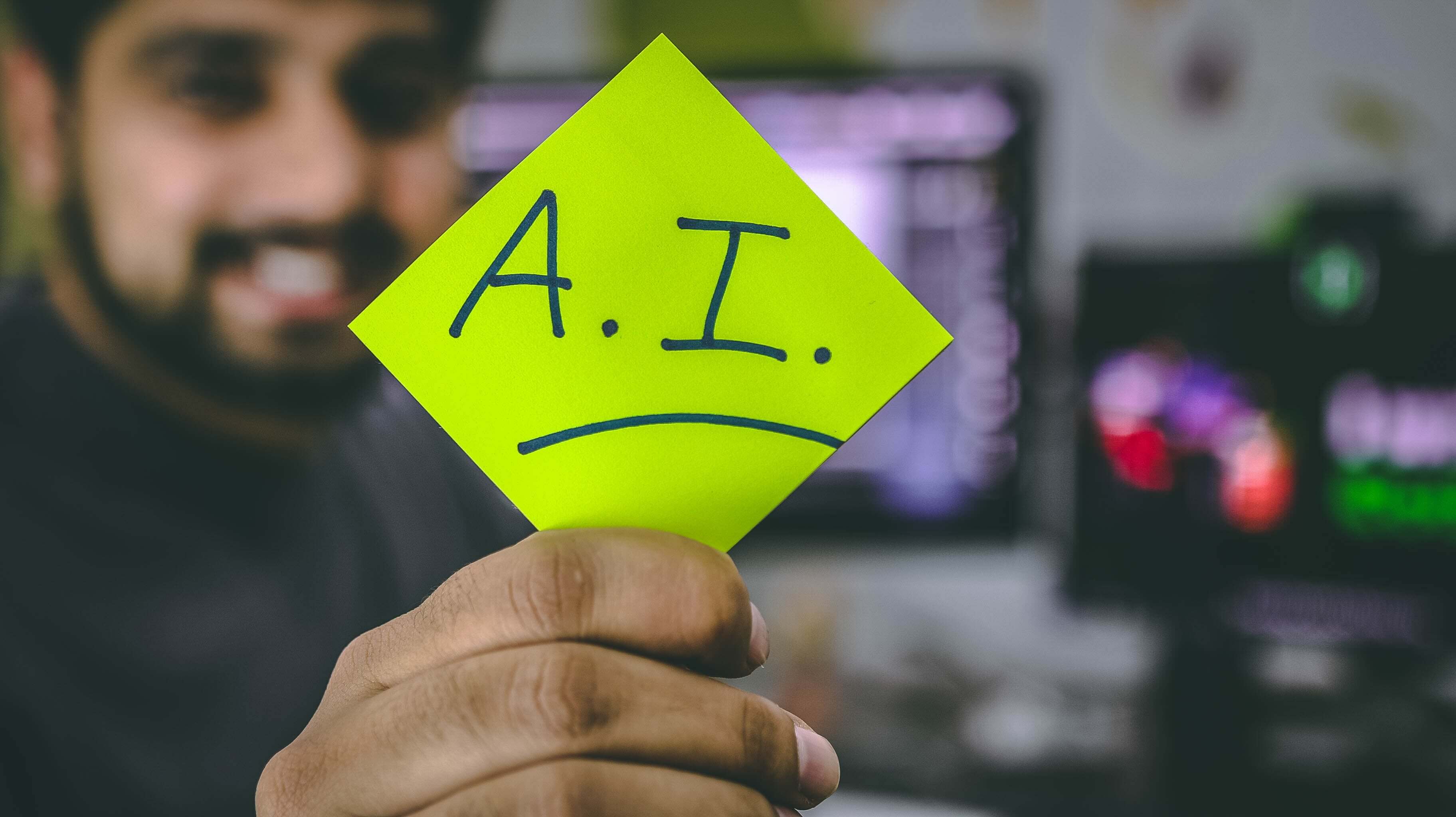 man holding a post-it that has A.I. written on it