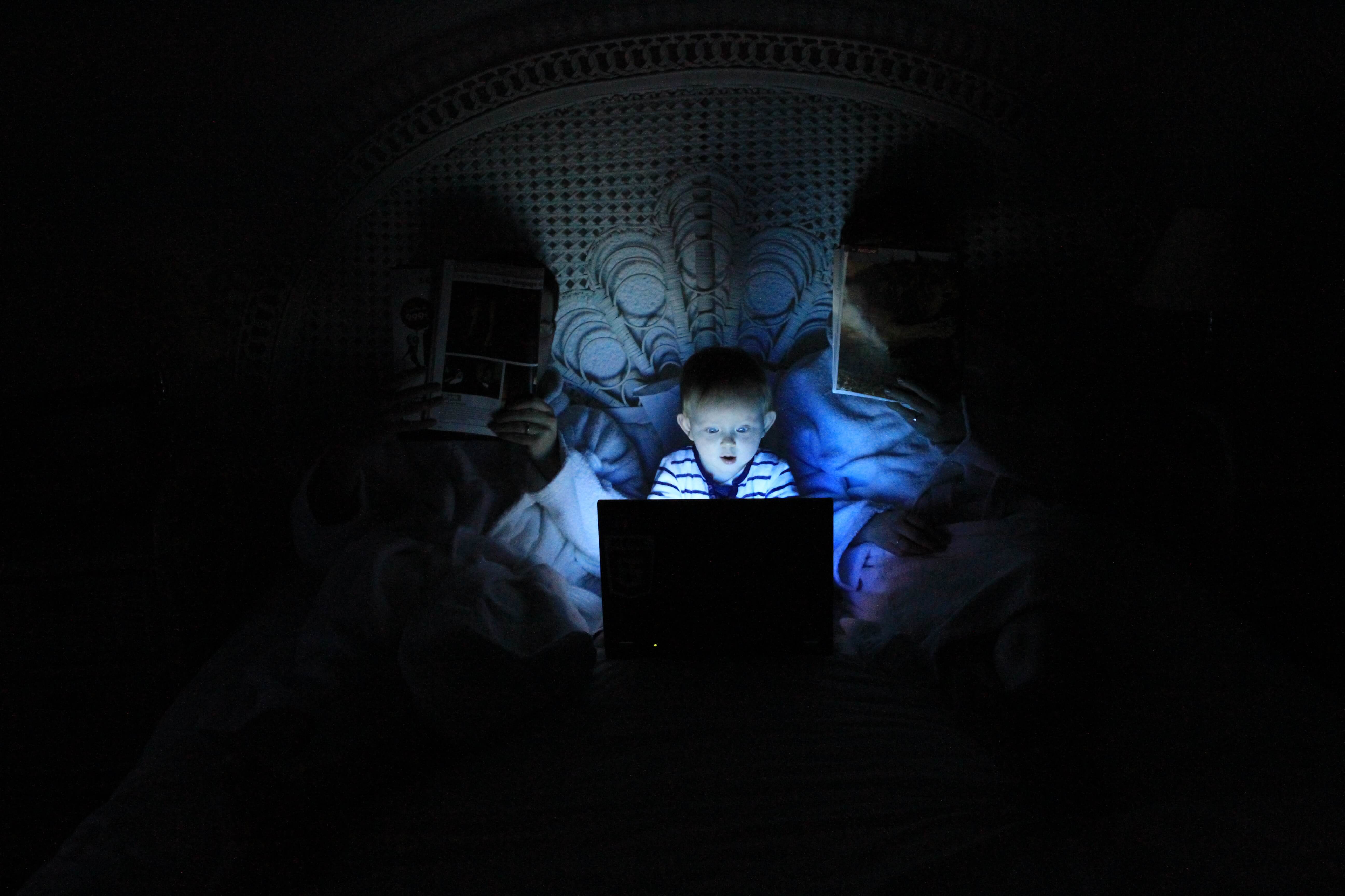 Child in darkness looking at a computer screen